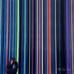 Strassenfotografie und Urbane Geometrie - Ein Mann am Telefon vor einem wand mit bunten Linien in la Defense