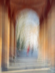 Fotoserie „Träumereien“ – Spiegelungen und Verwischungen - verschwommene Silhouetten von 2 menschen unter einer Arkade vom Südfriedhof in München